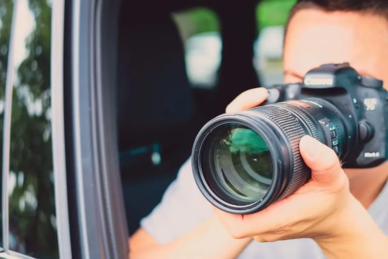 Privatdetektiv der Detektei für Brohltal fotografiert mit Kamera aus Autofenster, professionelle Observation durch Ermittler.