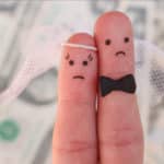2 Finger die eine Braut und einen Bräutigam darstellen, Im Hintergrund verlorenes Geld durch einen Heiratsschwindler