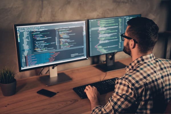 IT Experte an PC mit zwei Bildschirmen