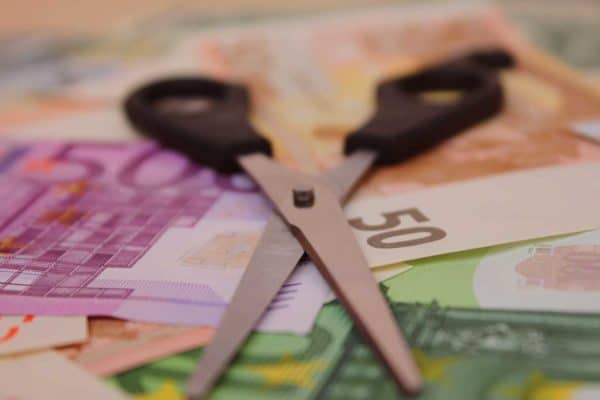 Schere auf Stapel Geld. Geld geht durch Korruption verloren