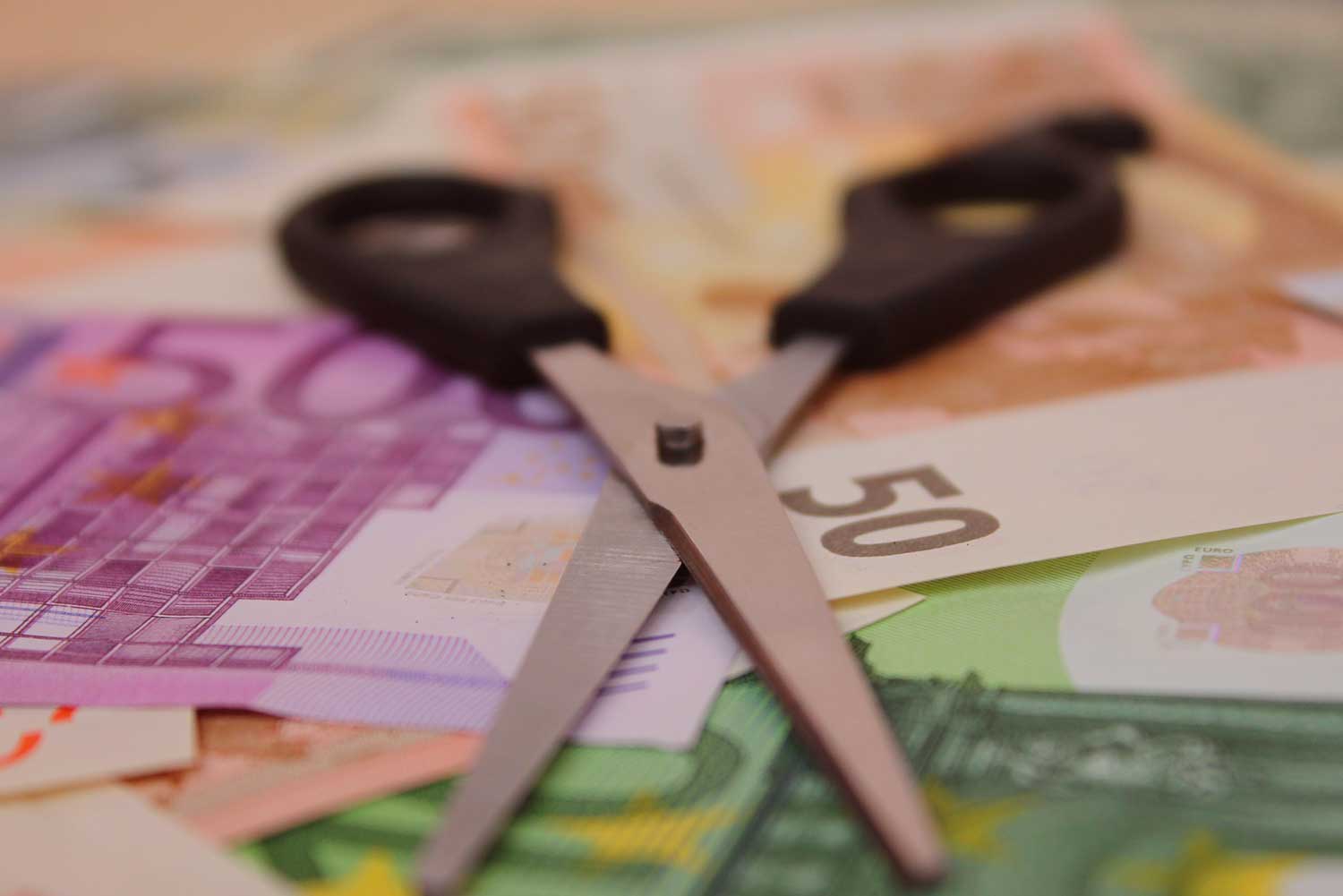 Schere auf Stapel Geld. Geld geht durch Korruption verloren