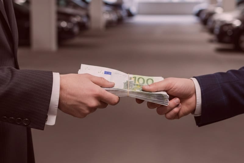 Detektive in Anzügen übergeben Geldbündel in Tiefgarage, diskrete Ermittlungen, geheime Geldübergabe mit Autos im Hintergrund.