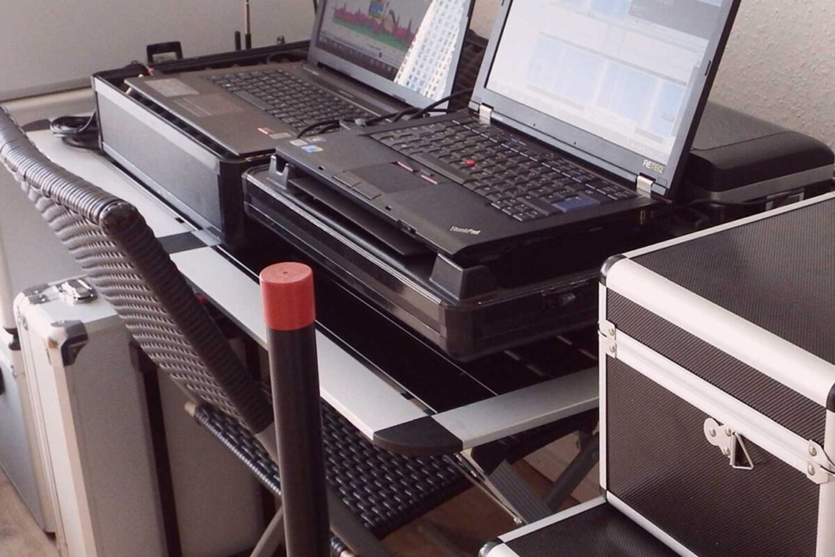 Zwei geöffnete Laptops und Detektei-Equipment auf einem Schreibtisch, professionelle Arbeitsumgebung für Privatdetektive.