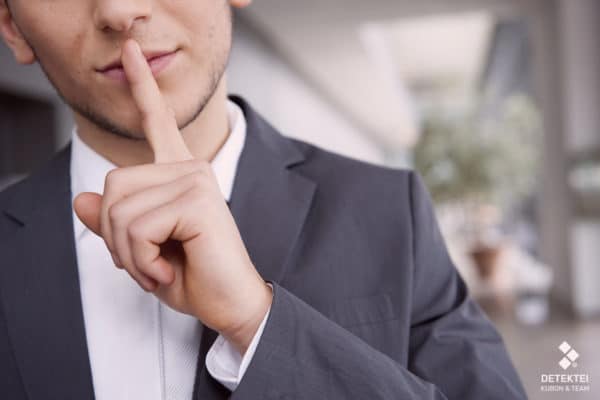 Detektiv hält Zeigefinger vor den Mund