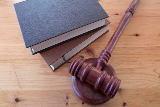 Holzhammer, Gericht und zwei Gesetzes-Bücher liegen auf einem Tisch