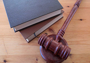 Holzhammer, Gericht und zwei Gesetzes-Bücher liegen auf einem Tisch